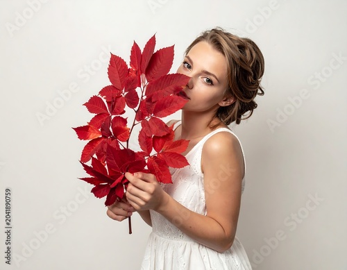 Young Woman Holding Bright Red Autumn Leaves in Minimal Studio Setting