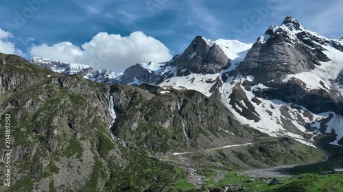Waterfalls cascading down rocky slopes below jagged snow-covered Pyrenees peaks