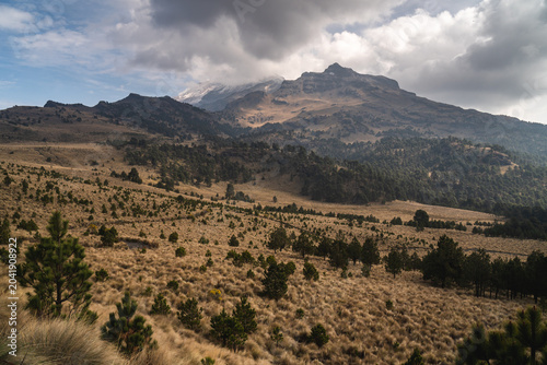 Scenic view of Popocatépetl volcano in Mexico with cloudy sky and lush vegetation during daytime ideal for travel and adventure enthusiasts