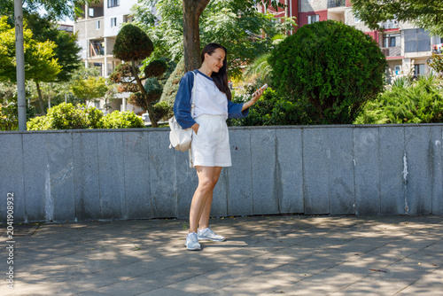 Foto Smiling woman with smartphone walking on city street