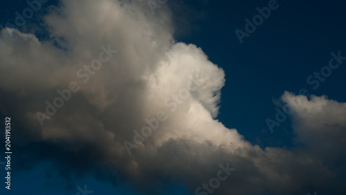 Dark gray rain clouds and a white cloud in the evening sky banner.