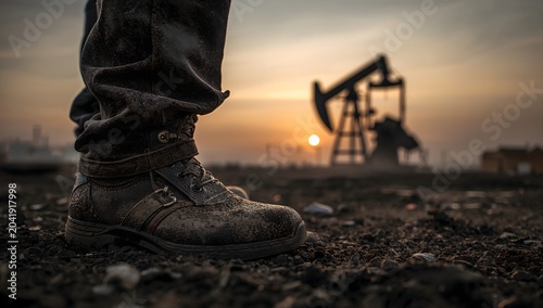 Close up of industrial safety boot with oil pump jack at sunset