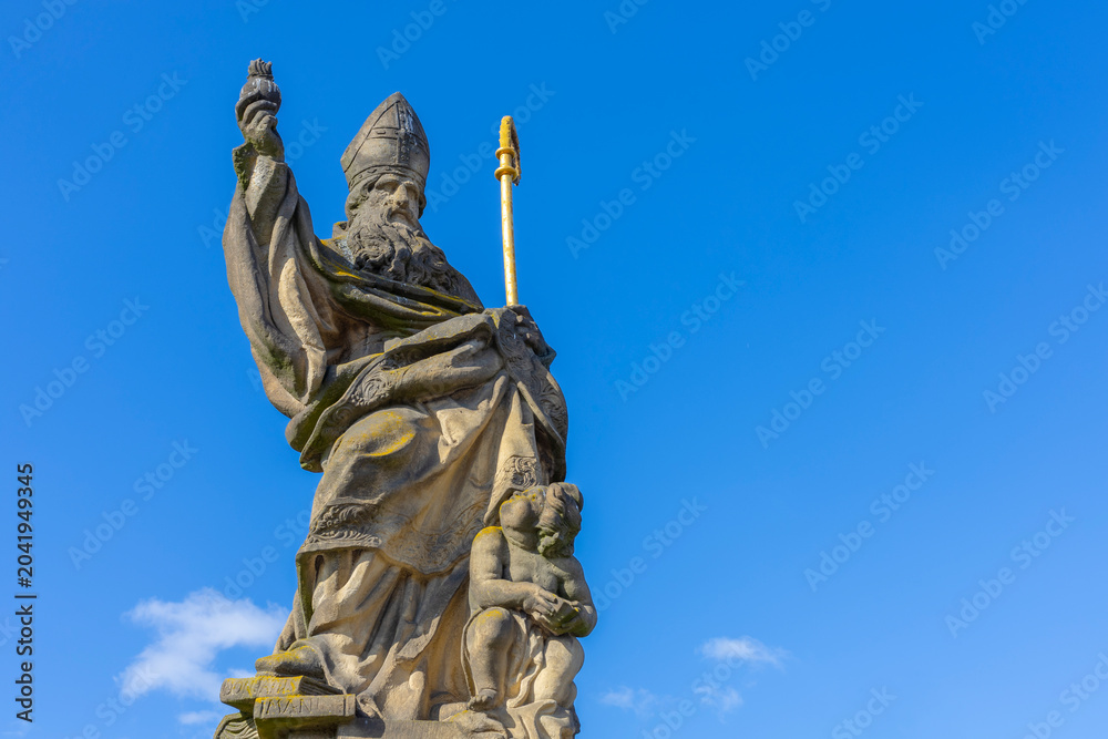 Obraz premium Low angle view of the historic Statue of Saint Augustine of Hippo holding a burning heart on Charles Bridge, Prague.