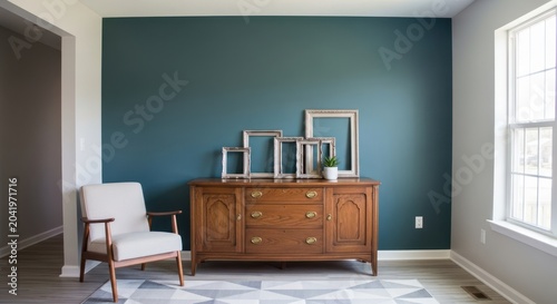 Minimalist living room with teal wall and wooden dresser.