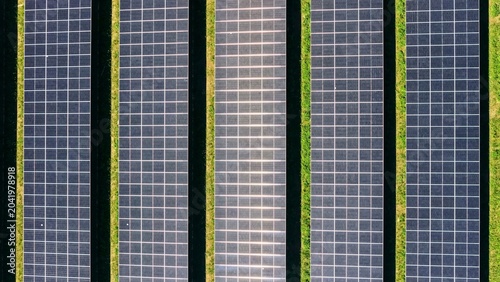 Schilderij op canvas Aerial View of Parallel Solar Panel Rows with Green Vegetation