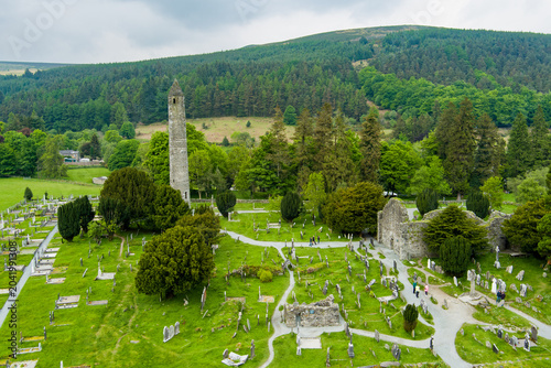 Aerial view of ancient cemetery and round tower at Glendalough Monastic Site in County Wicklow, Ireland. Historic Irish landmark in Wicklow Mountains National Park
