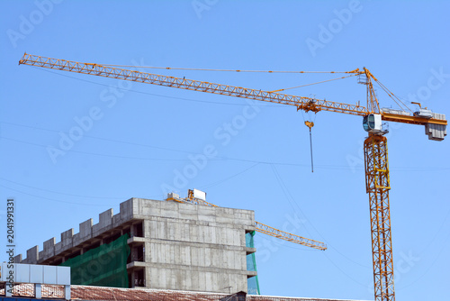 Construction of a new residential complex with cranes in the city. Construction of a multi-storey building with cranes in the background. Rise building in the city
