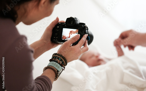 Quadro su tela Woman Takes Pictures Of Newborn Baby While Mom Holds Baby Hand