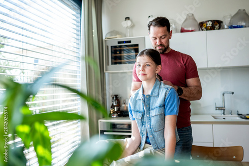 Fotografia Dad brushing daughter hair and making braid at home.