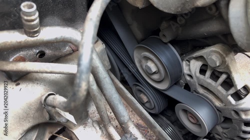 Close-up of moving engine drive belts and pulleys in a running automobile engine, showcasing mechanical motion, automotive technology and vehicle maintenance