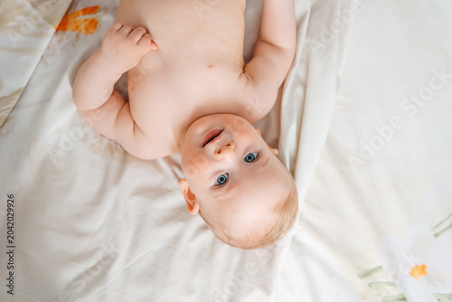 Top view of a sweet bare skin baby lying down on a white bed