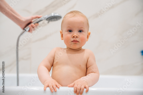Serious Baby Leaning on Bathtub Edge