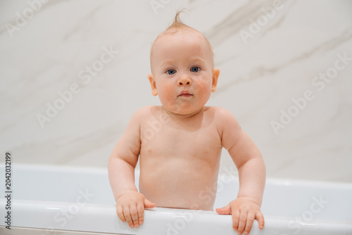 Portrait of a Curious Baby Standing in a Bathtub