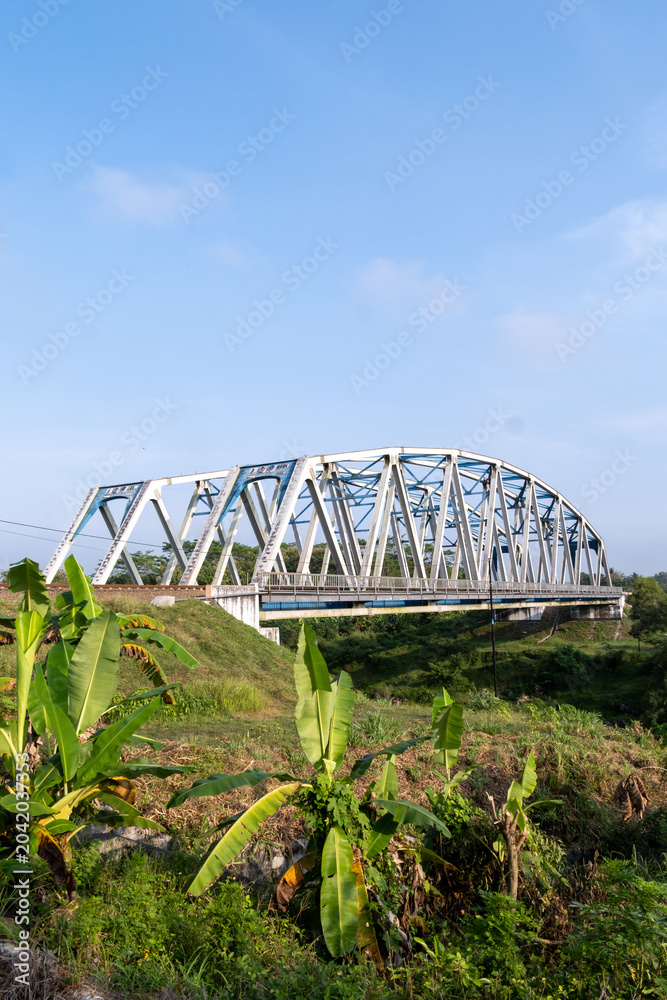 Fototapeta premium The historical Renville railway steel truss bridge under a clear blue sky in Kebumen, Central Java, Indonesia.