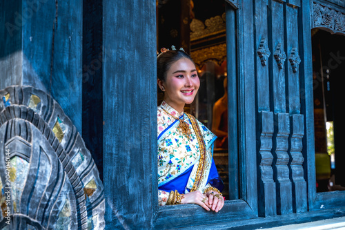Portrait Thai woman in elegant traditional Thai dress standing at historic temple window