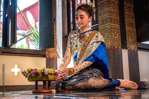 Foto Elegant Asian woman in beautiful Thai traditional dress sitting respectfully ins