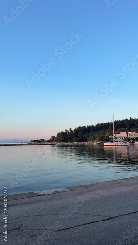 Golden orange sunset over a glassy calm sea, peaceful bay, mirror-like water, natural coastal landscape, serene evening atmosphere
