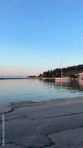 Golden orange sunset over a glassy calm sea, peaceful bay, mirror-like water, natural coastal landscape, serene evening atmosphere