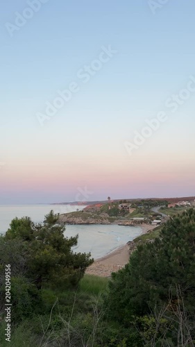sunset over tSunset sea view through trees, gentle waves, calm atmosphere, golden light, peaceful coastal landscape, cinematic nature videohe sea