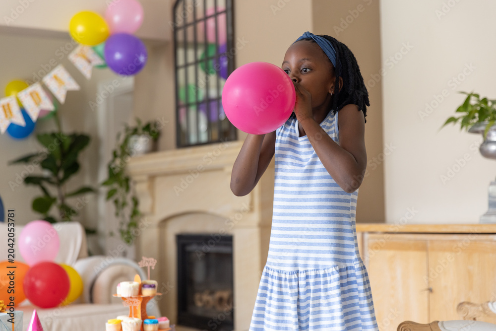Obraz premium Pink balloon is being inflated in living room with cupcakes, banner, sofa, fireplace, potted plants