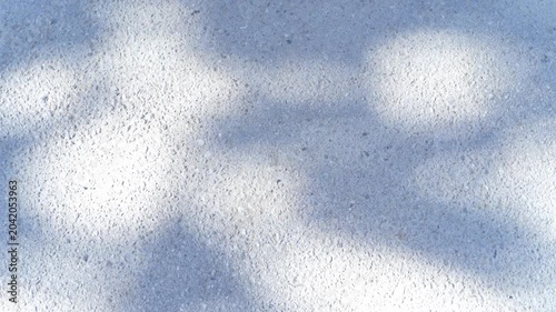 Blue surface with a leaf and foliage shadows moving in the wind on a sunny day