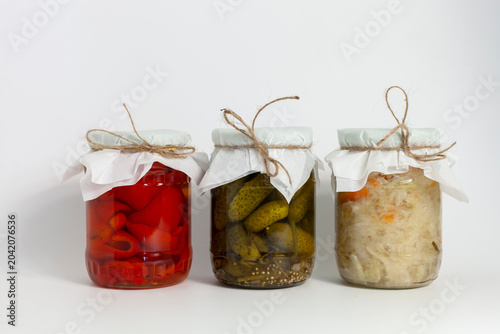 фотографія Assorted homemade pickled vegetables in glass jars on white background