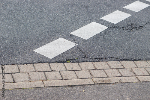 Foto White pedestrian crosswalk markings on asphalt road surface adjacent to a brick