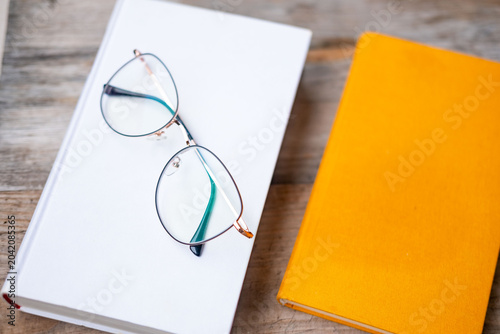 Φωτογραφία Yellow hardcover book with glasses on table background, top view reading or stud