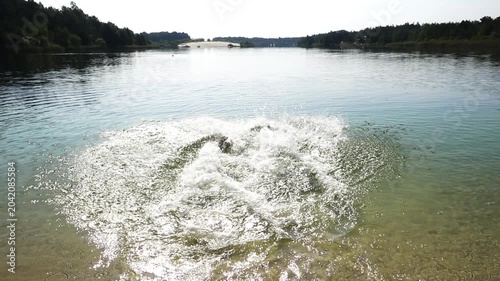 Two sisters dive into a big lake. Summer nature.