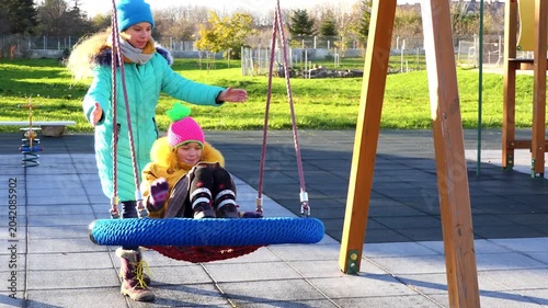 two beautiful girls ride a round swing in the autumn zoo