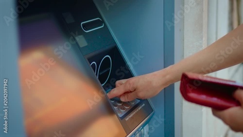 Entering PIN code on outdoor ATM keypad during banking transaction and cash withdrawal. Female hand using automated teller machine for secure financial operation in public location. Digital banking
