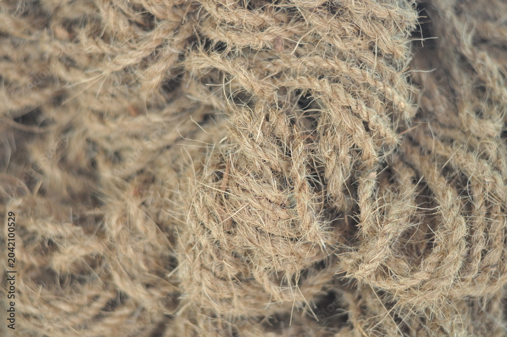 Obraz premium A bunch of tangled brown rope. The rope is knotted and tangled, and it looks like it has been used for a long time. The image has a rustic and worn-out feel to it