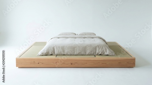 Modern minimalist platform bed with beige bedding on tatami mat in white room interior design