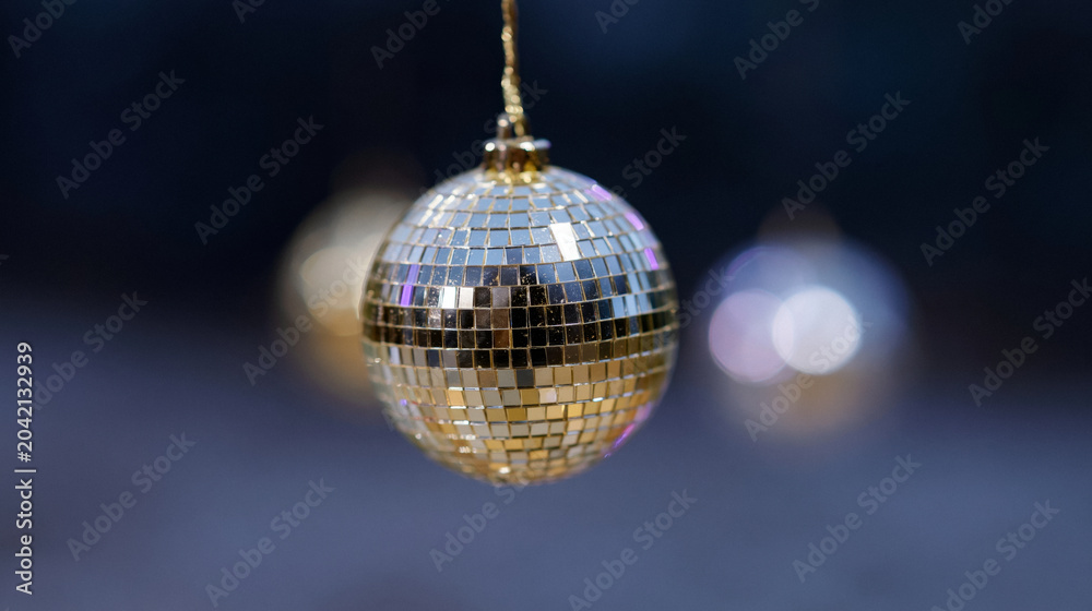Obraz premium A shiny golden disco ball hangs, reflecting light at a vibrant nightlife party celebration.
