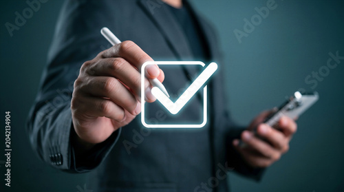 Businessman drawing a glowing digital checkmark, Symbolizes task completion, approval, success, and achieving business goals