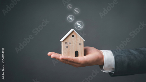 Businessman holding a wooden house with percentage icons, Ideal for mortgage, interest rate, and real estate finance