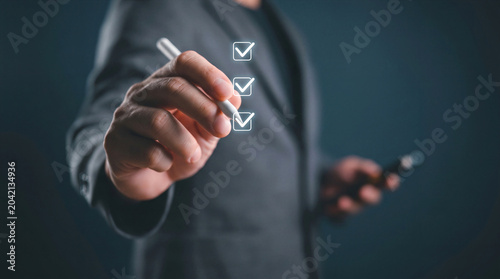 Businessman using a digital pen to complete a checklist, symbolizes task management, success, productivity, and completed goals