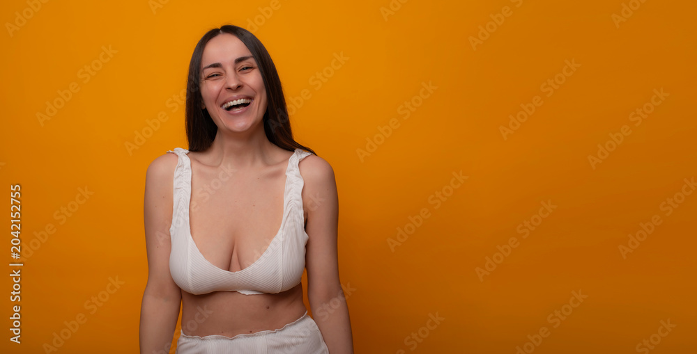 Obraz premium Laughing makeup-free woman on orange background with copy space