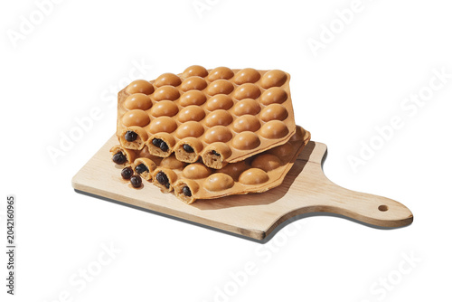 Famous Hong Kong style egg waffle bubble waffle filled with tapioca boba pearls on a wooden cutting board, isolated.
