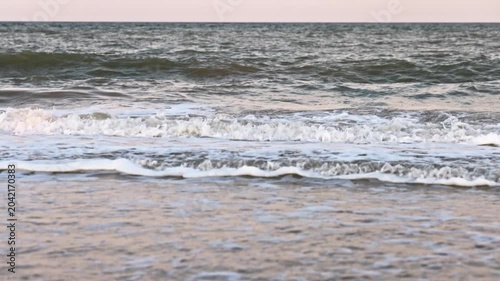 The sea under a cloudy sky with clouds on the beach with a lot of seashells