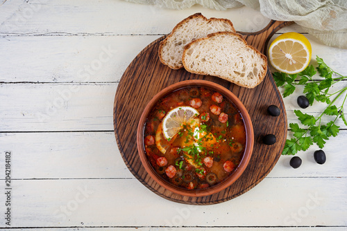 Bowl of traditional Solyanka soup with mixed meats and olives. Hearty homemade Eastern European dish