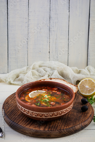 Bowl of traditional Solyanka soup with mixed meats and olives. Hearty homemade Eastern European dish