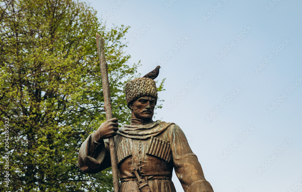 Obraz premium Bronze warrior statue with a pigeon on its hat in Vladikavkaz on a sunny spring day in North Ossetia, Russia