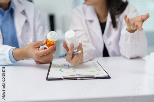Healthcare workers comparing medicine bottles, discussing pharmaceutical treatment plans and patient health data in a clinical environment