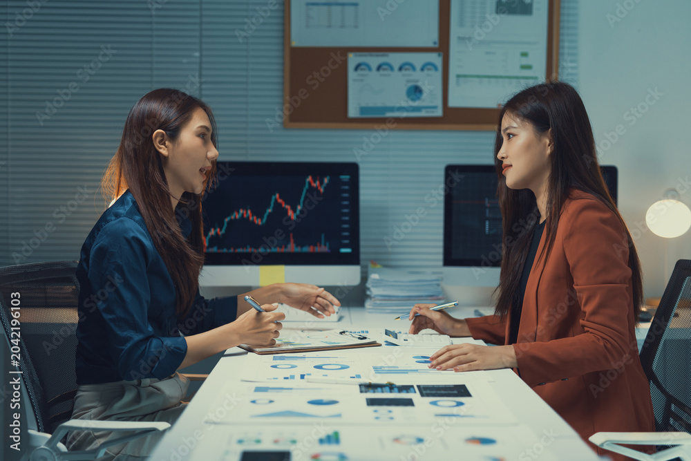 Fototapeta premium Business women discussing financial data, analyzing stock market trends, and planning corporate strategy in a modern office