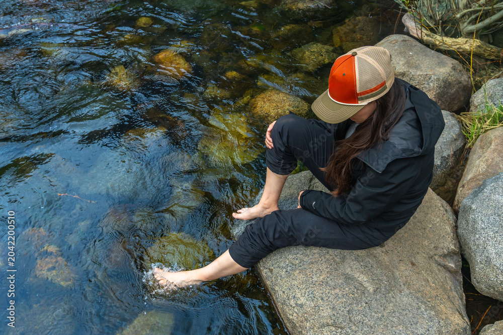 Wall Mural Woman relaxing in cold stream water on a summer day