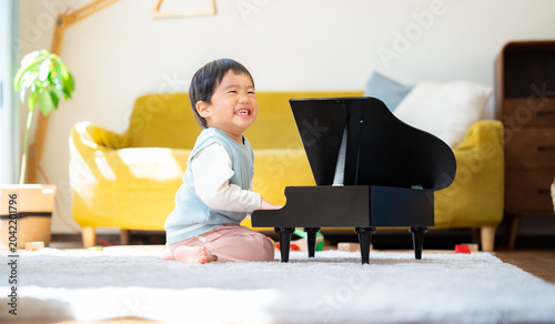 Foto リビングでおもちゃのピアノを弾く3歳の男の子