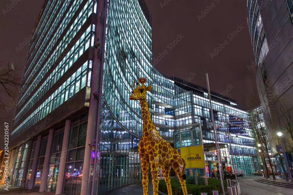 Naklejka premium Huge plastic giraffe statue in front of the Legoland Discovery center, night shot in Berlin, Germany