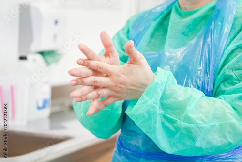 A medical professional rubs their hands together after applying antiseptic sanitizer in a bright clinical ward to ensure proper hygiene and prevent the spread of harmful infections