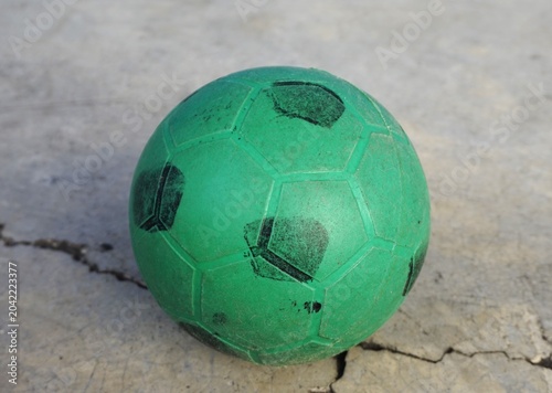 Green plastic ball on cement floor, children's toy